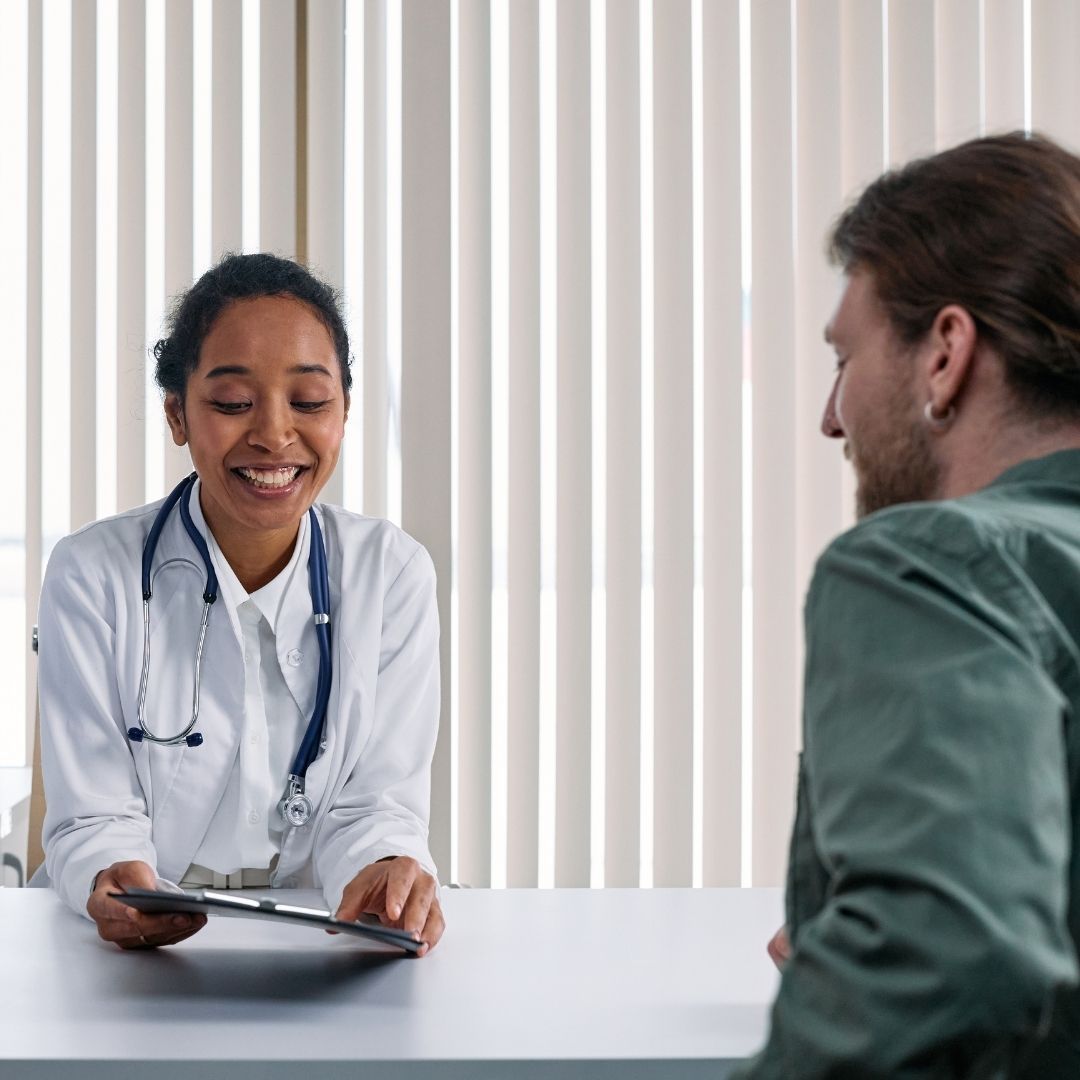 Smiling doctor reviewing medical chart with a patient.