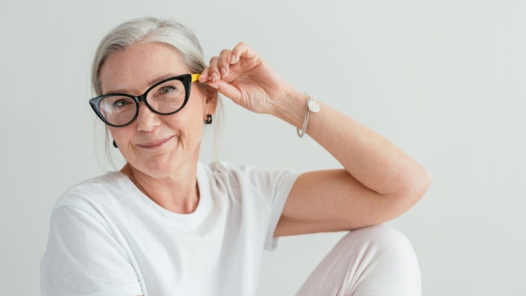 Smiling mature woman with silver hair and glasses.