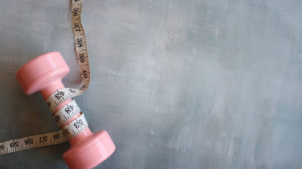Pink dumbbell wrapped in white measuring tape.