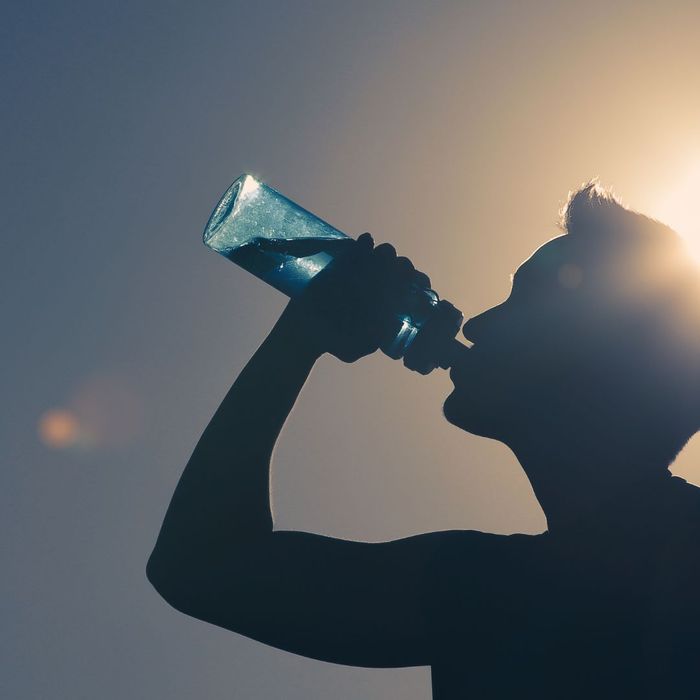 Silhouette of a person drinking water from a bottle.