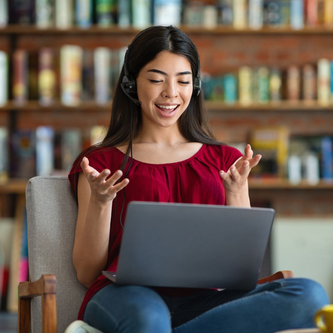 Smiling woman with headset working on her laptop.