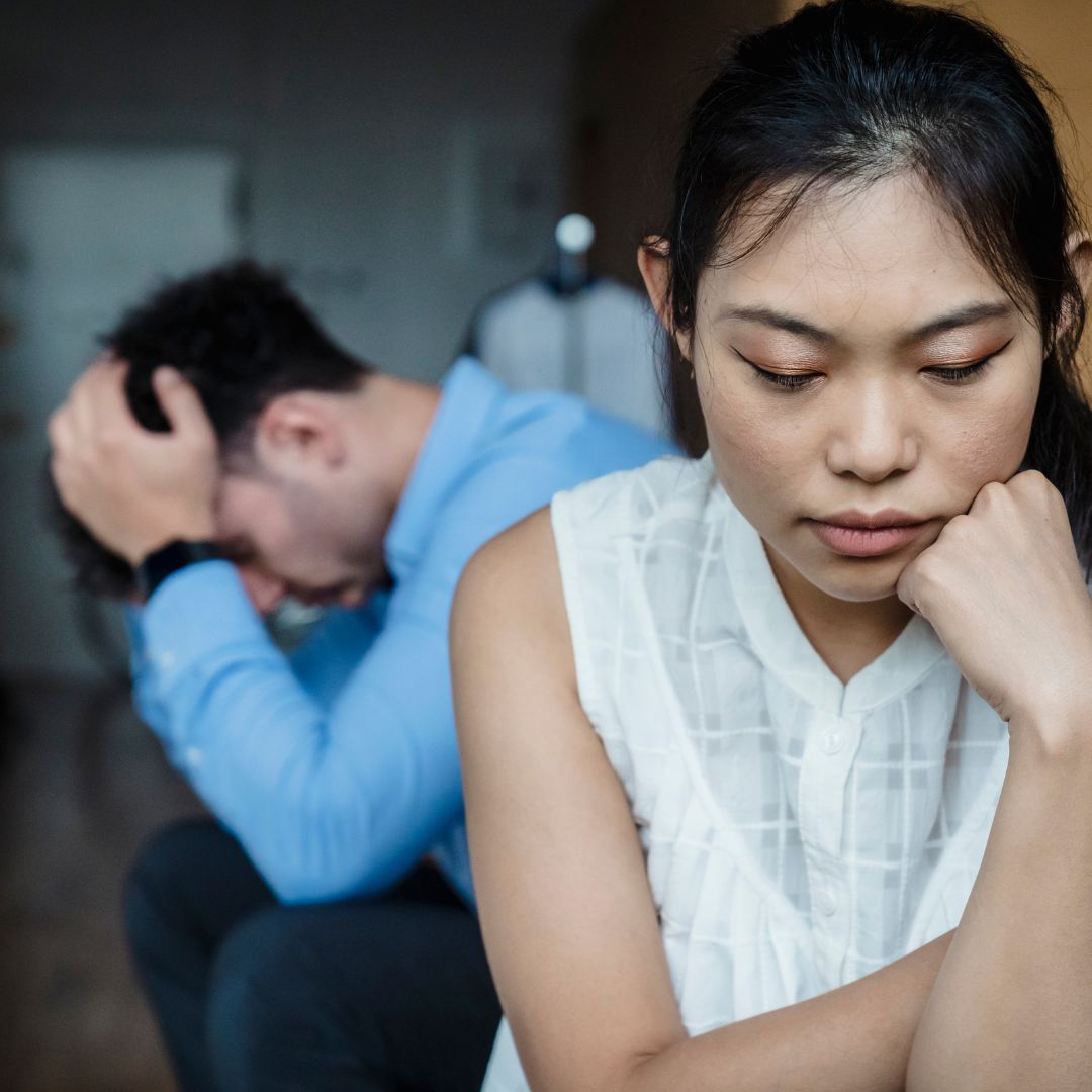 Sad woman with stressed partner sitting in background.