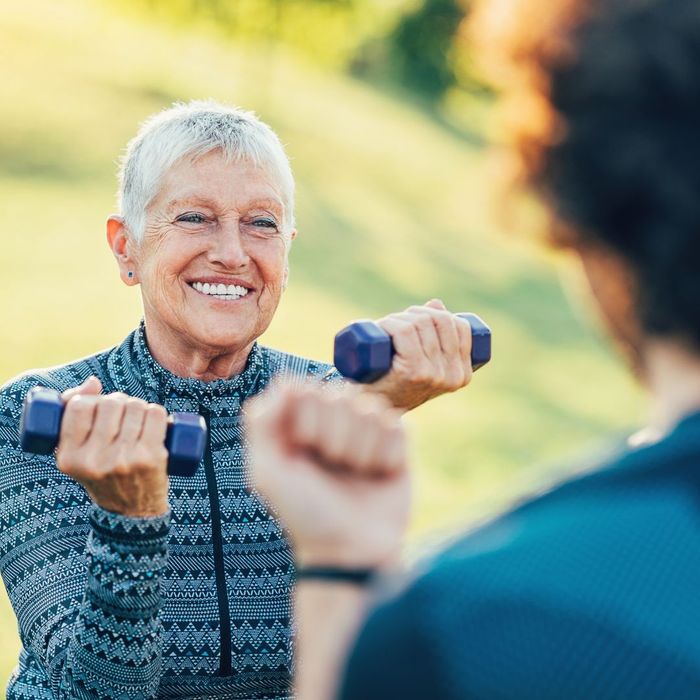 Smiling senior woman lifting small dumbbells during workout.